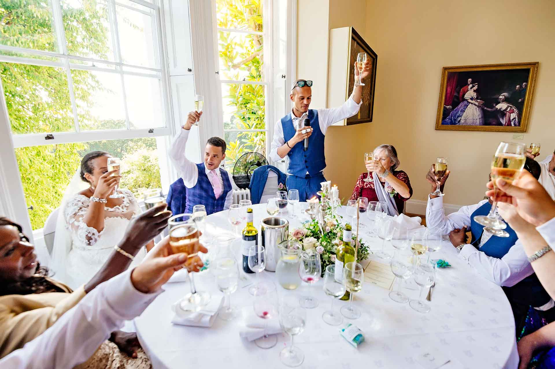 Wedding Guests Toast Bride Around Round Table at Pembroke Lodge in Richmond Park