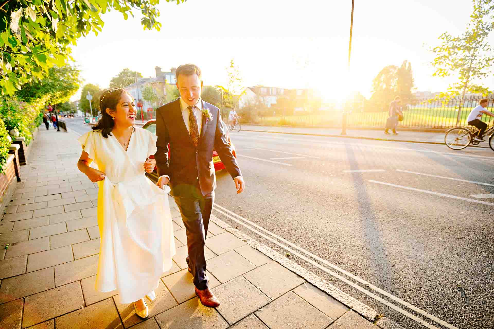Newly-weds walking and smiling in late afternoon sun in London during their portraits