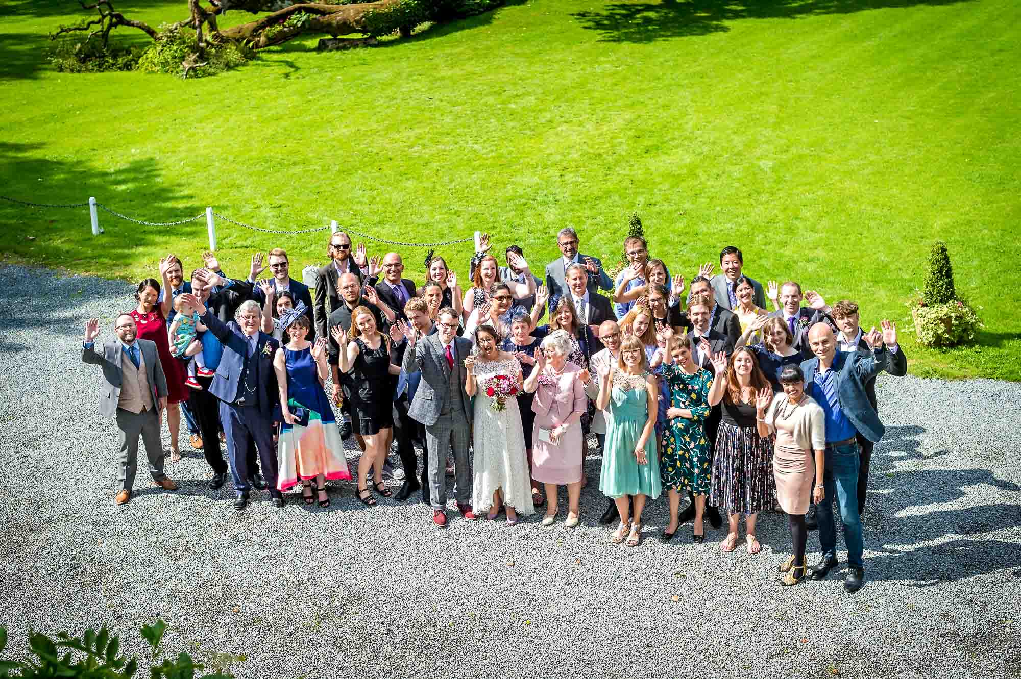 The entire wedding party waving in group photo outside Plas Glansevin
