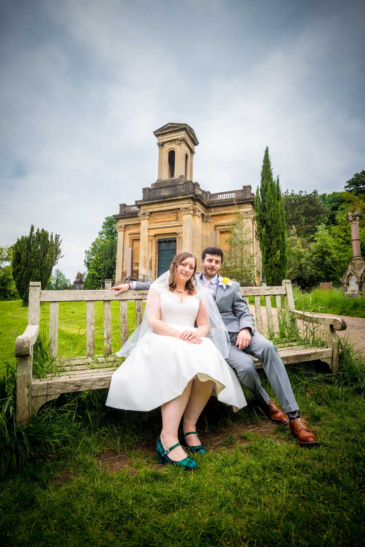 Couple sitting on a bench with the Anglican Chapel in the background at Arnos Vale.