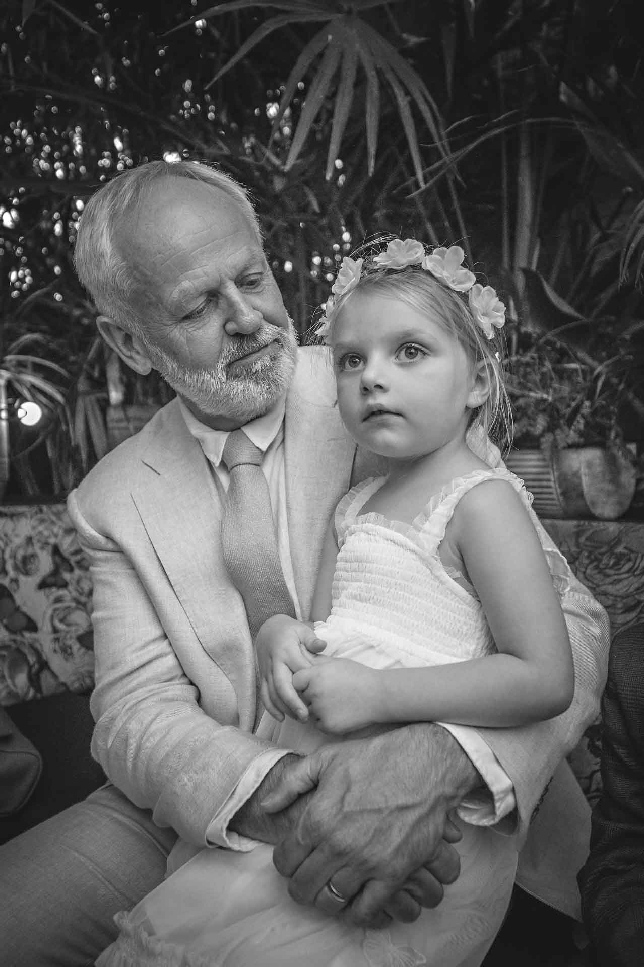 Girl sitting on lap of grandfather with white beard