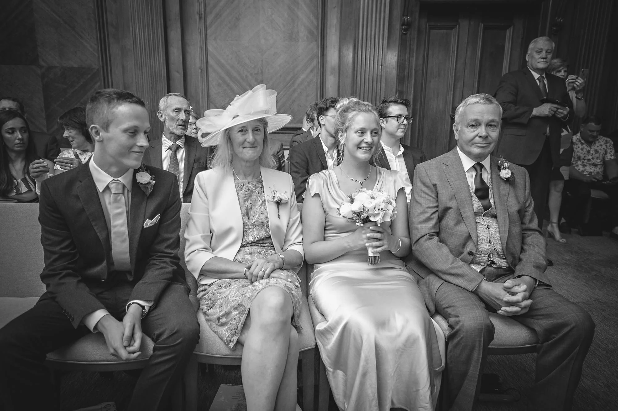 Vier Hochzeitsgäste in der ersten Reihe vor der Hochzeit in der Old Marylebone Town Hall, London