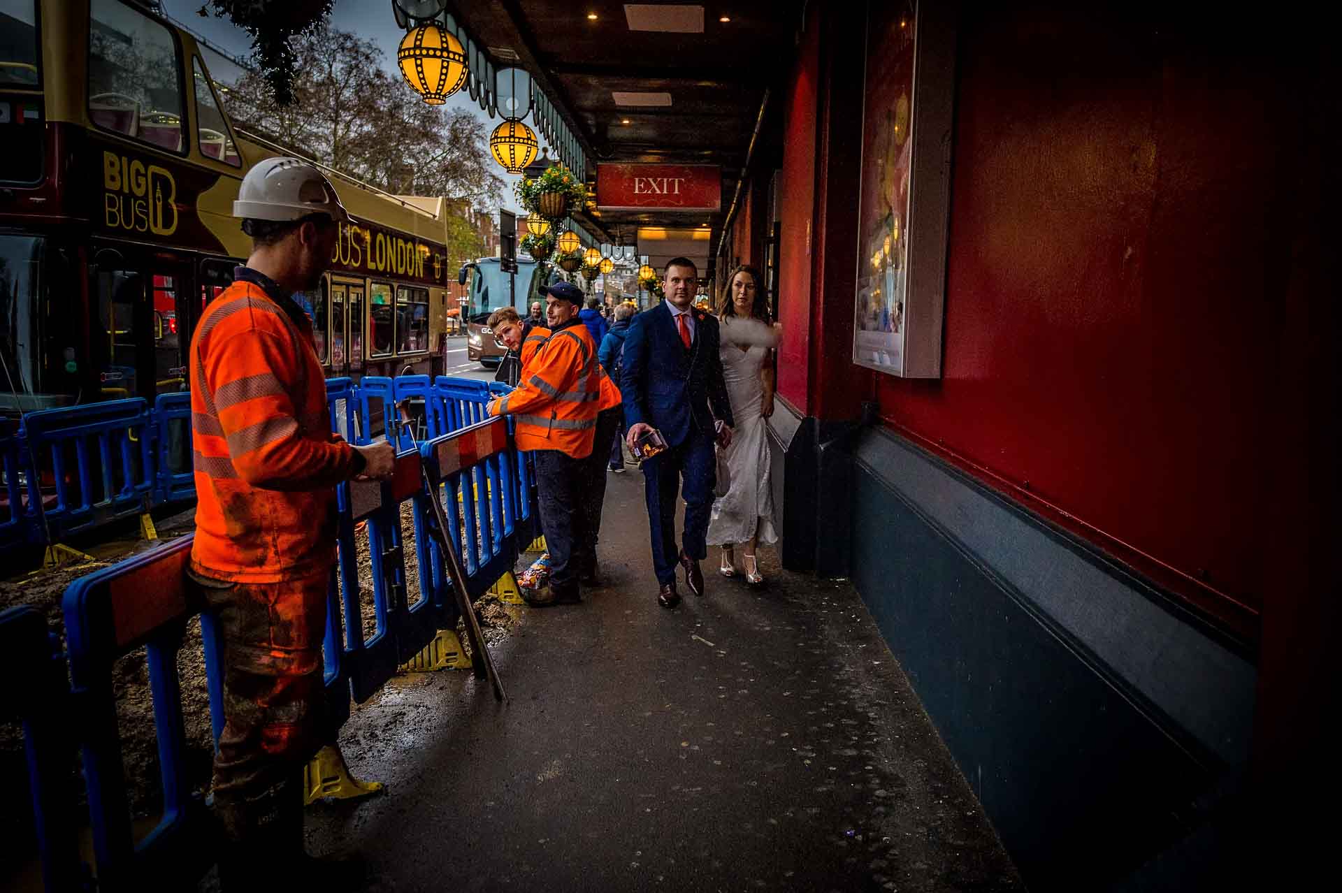 Wedding portrait of couple walking through roadworks in London by Madame Tussauds